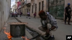 Un hombre cocina sopa sobre una fogata en una acera, durante un apagón en La Habana, Cuba, el miércoles 4 de diciembre de 2024. (Foto AP/Ramon Espinosa)